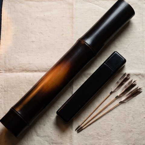 Fukiya — tube, lacquered case, twenty darts, photographed on unbleached hemp cloth.