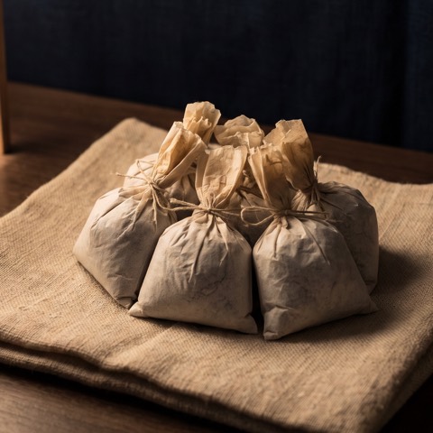 Metsubushi — six packets, photographed on unbleached hemp cloth.
